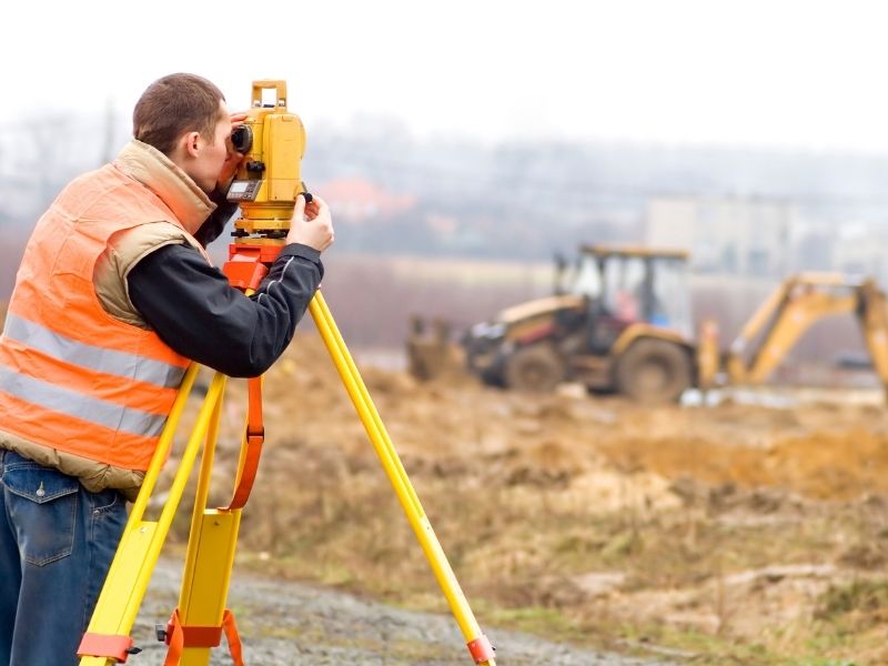 Surveyor performing construction surveys to guide site preparation before building begins