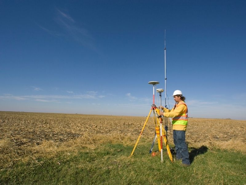 Land surveyor conducting a topographic survey to measure site elevations before construction begins