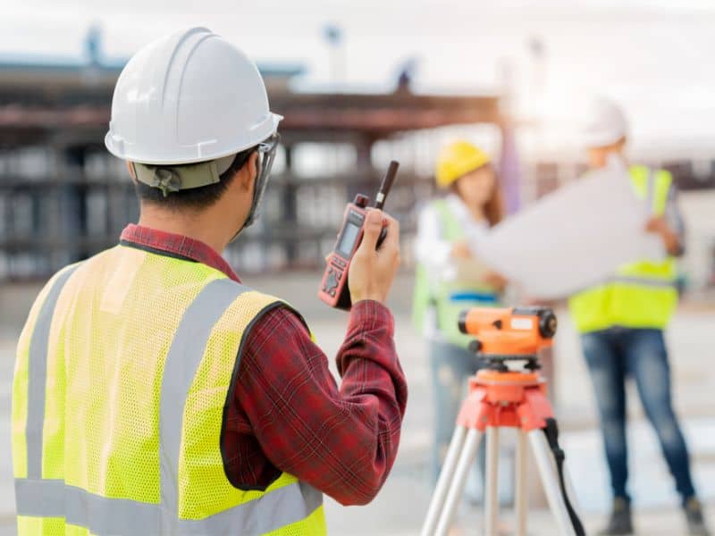 Licensed surveyors conducting field measurements and reviewing plans during an ALTA survey for a commercial property to document boundaries and site improvements